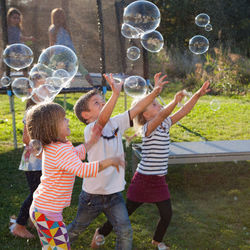 Full length of siblings standing at bubbles