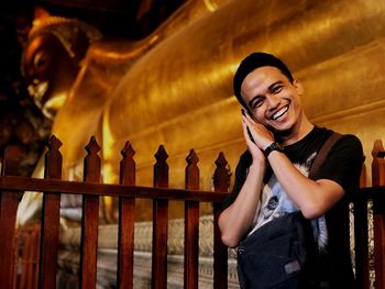 Portrait of smiling young man against buddha temple