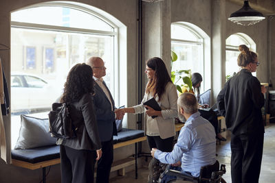 Business professionals greeting by colleague at creative office