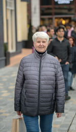 Portrait of woman standing on footpath in city