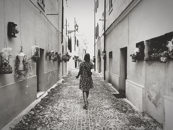 Rear view of woman walking on street amidst buildings