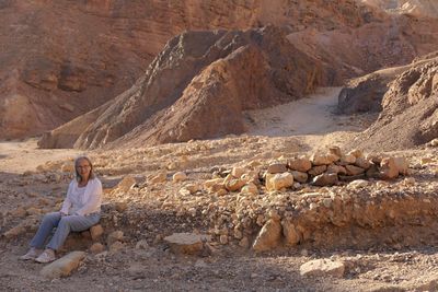 Senior woman sitting on rock against mountains at desert