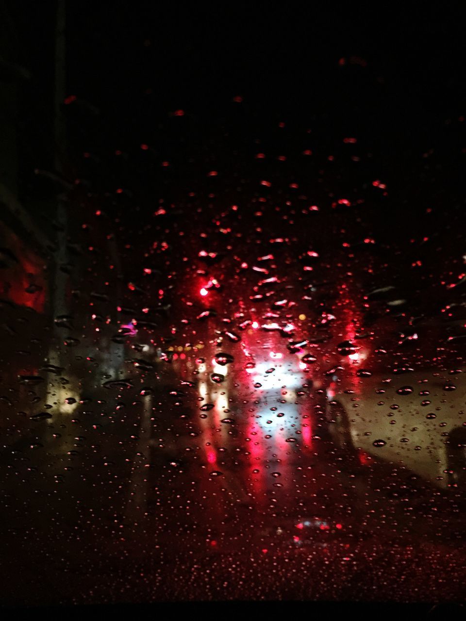 RAINDROPS ON GLASS WINDOW OF ROAD