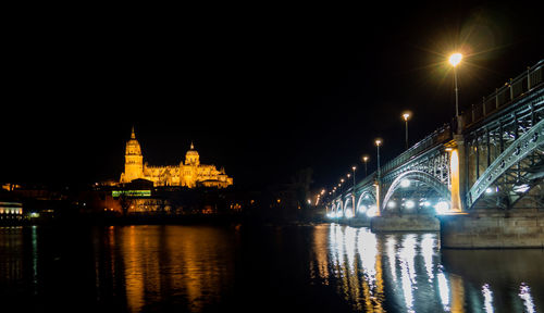 Illuminated bridge over river at night