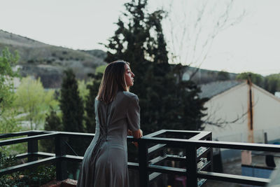 Woman standing by railing against sky