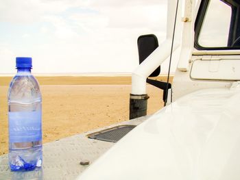 Close-up of bottle on beach against sky