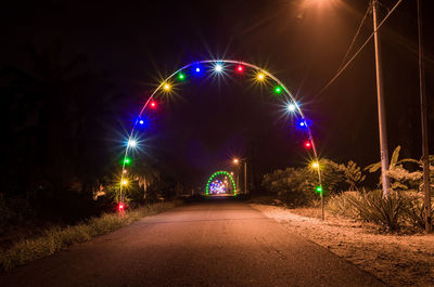 Illuminated light trails on road against sky at night