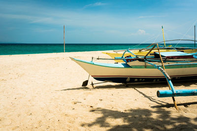 Deck chairs on beach against sky
