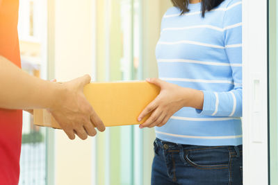 Midsection of woman holding hands at home