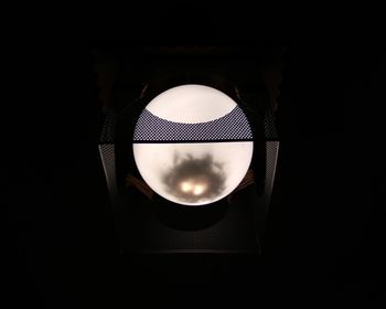 Low angle view of illuminated lamp against black background