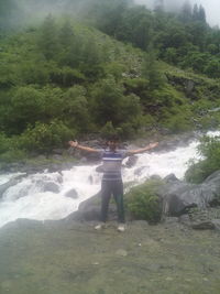 Rear view of woman standing at waterfall