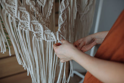 A young girl weaves macrame panels at home