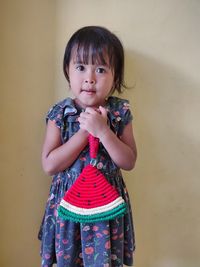 Cute girl looking away while standing against wall