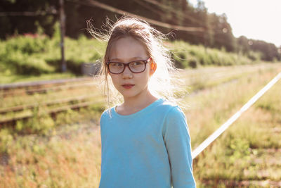 Girl looking away while standing against plants