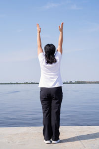 Rear view of woman standing in water against sky