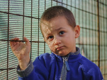 Portrait of boy against blue fence