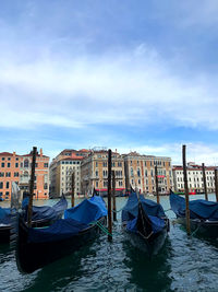 Gondolas moored on canal against buildings in city