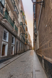 Walkway amidst buildings against sky