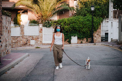 Full length of woman with dog walking in city