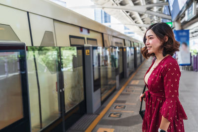 Woman standing by train at railroad station