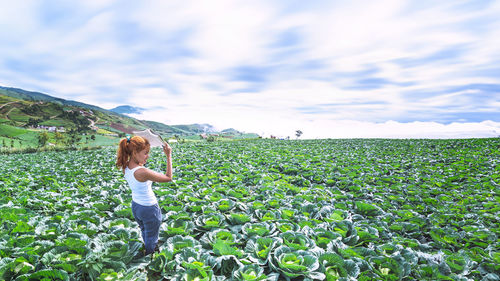 Rear view of woman standing on field against sky