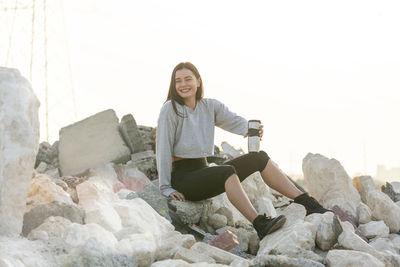 Portrait of smiling young woman sitting on rock