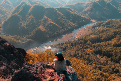 Rear view of woman sitting on mountain