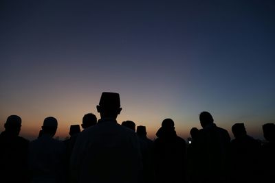 Silhouette men standing on field at sunset during eid-ul-fitr