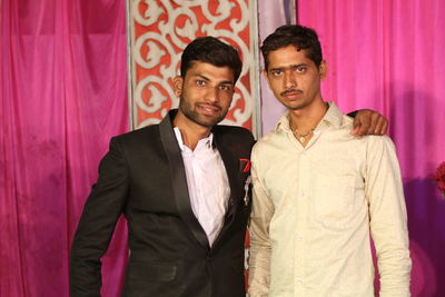 Portrait of brothers standing against curtain