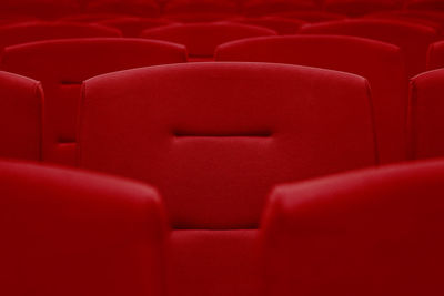 Rows of red velvet seats in a dark and totally empty movie theater.