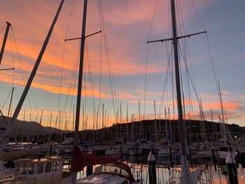 Sailboats moored at harbor during sunset