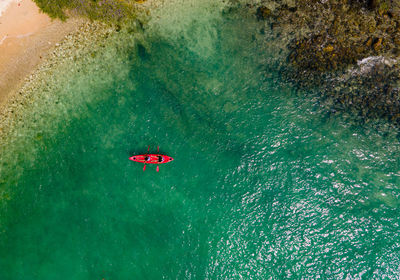 The top view of two tourist paddling their red kayak at the beautiful blue seashore in summer