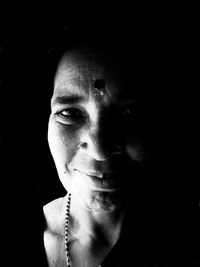 Close-up portrait of young woman against black background