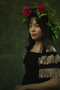 Portrait of beautiful woman standing by flower plant