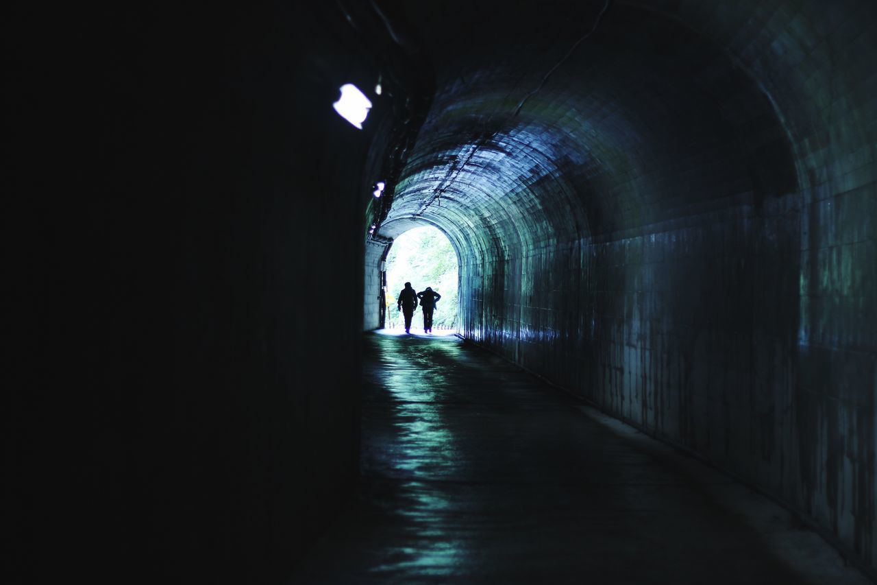 SILHOUETTE PEOPLE WALKING ON FOOTPATH IN TUNNEL