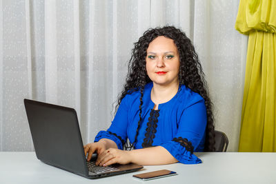 Portrait of woman using phone while sitting on table