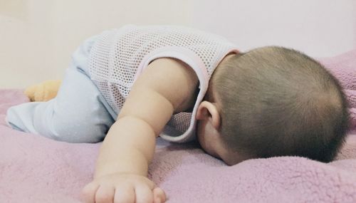 Midsection of baby sleeping in bed