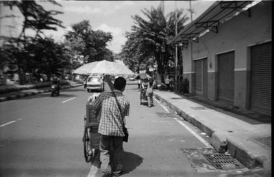 Rear view of man with push cart on street