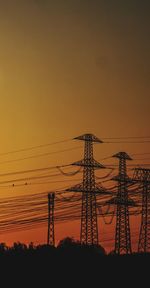 Low angle view of silhouette electricity pylon against sky during sunset