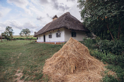 House on field by trees against sky