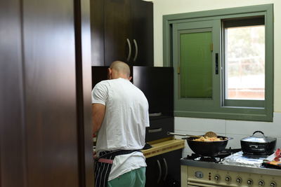 Rear view of man cooking in kitchen