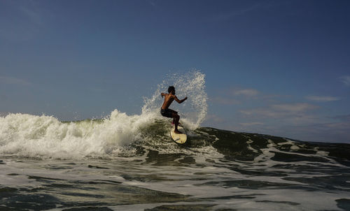 Man splashing water in sea against sky