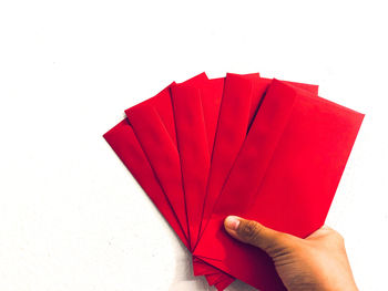 Close-up of hand holding paper against white background