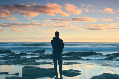 Silhouette man standing on beach against sky during sunset