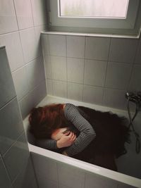 High angle view of woman lying down on tiled floor