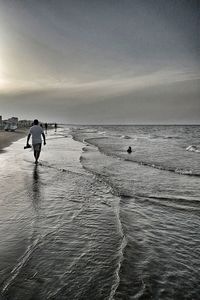 Rear view of man on beach against sky