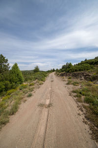 Dirt road along landscape against sky