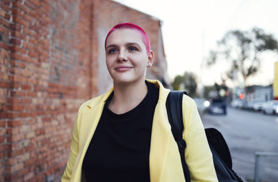 Portrait of young woman standing against wall