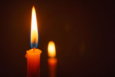 Candle lit in the dark, candle flame at night, burning candle on black background.