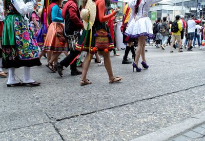 Low section of people walking on street in city